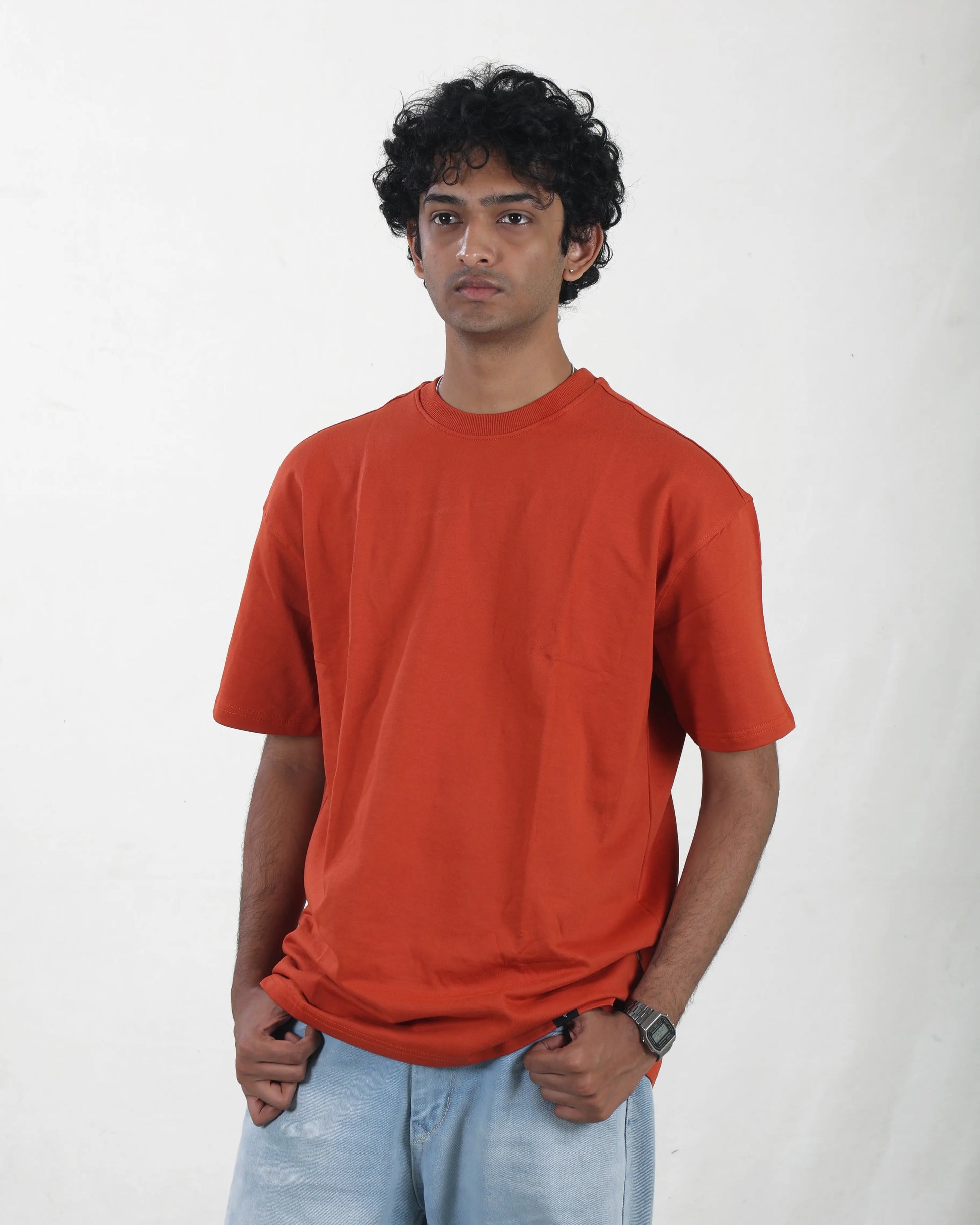 Person wearing an orange t-shirt and light blue jeans on a white background