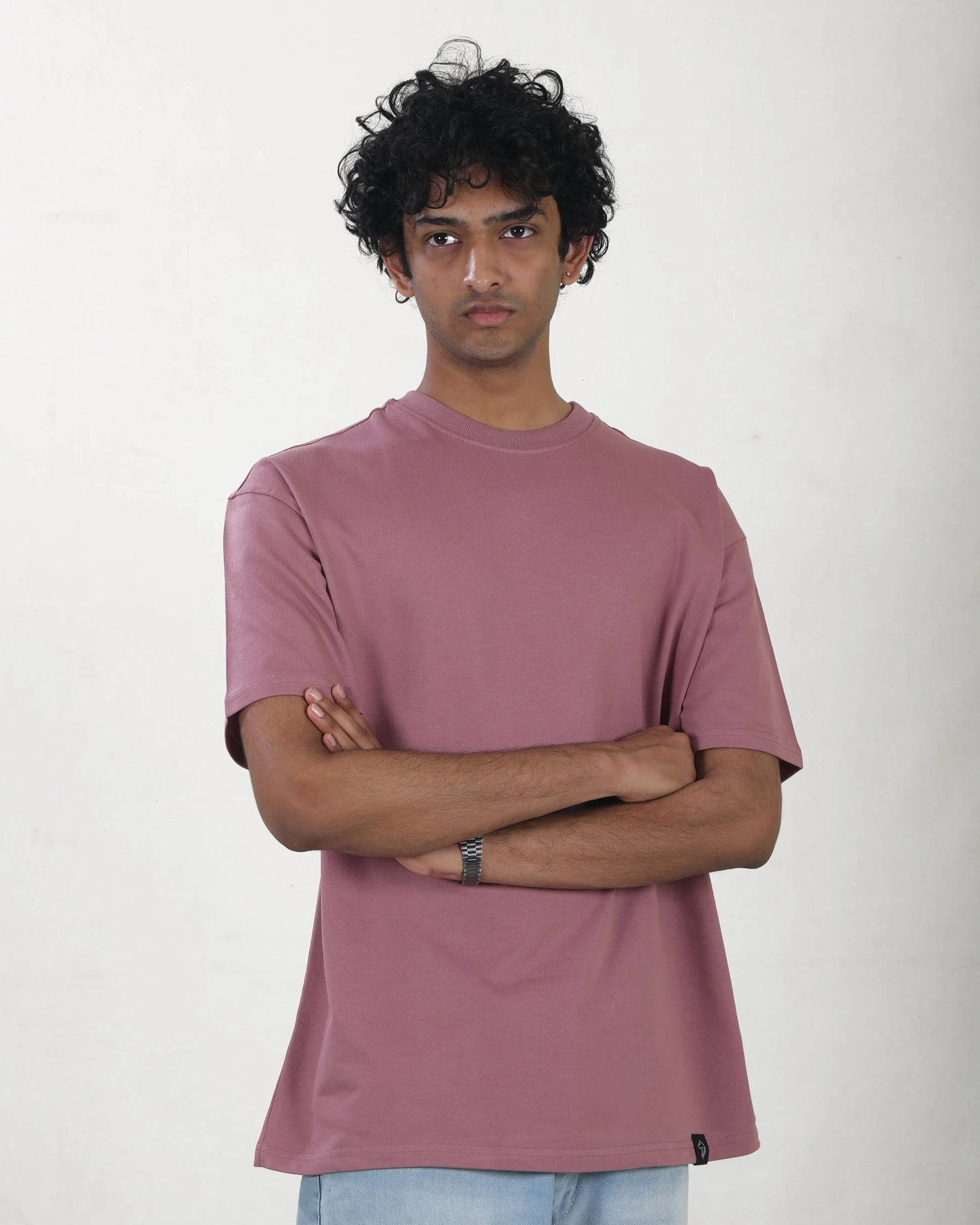 Person wearing a mauve t-shirt against a plain background