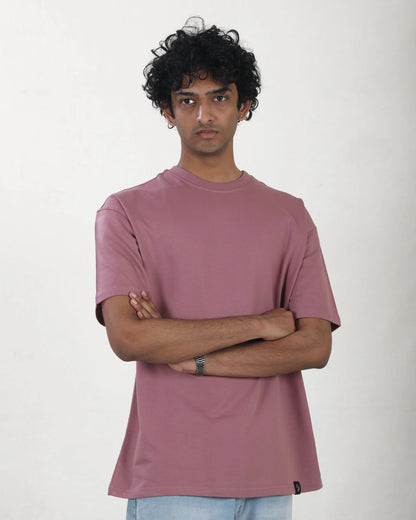 Person wearing a mauve t-shirt against a plain background