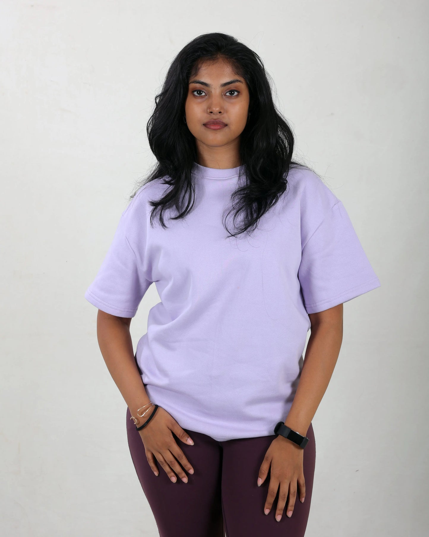 Woman wearing a light purple t-shirt and maroon pants against a plain background