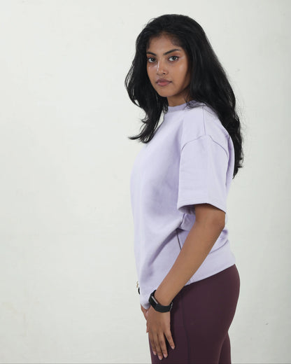 Person wearing a light purple oversized t-shirt and maroon pants on a white background