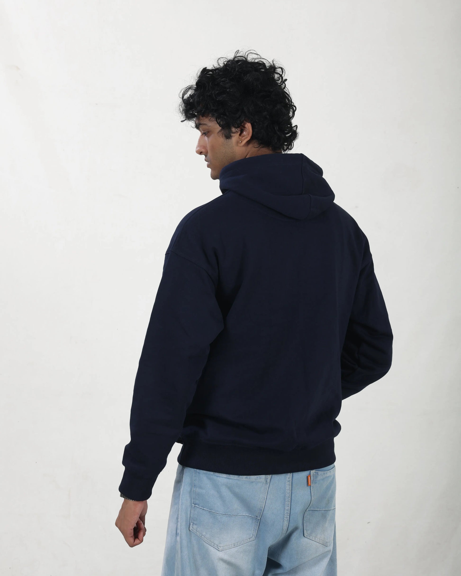 Person wearing a navy hoodie from behind on a white background