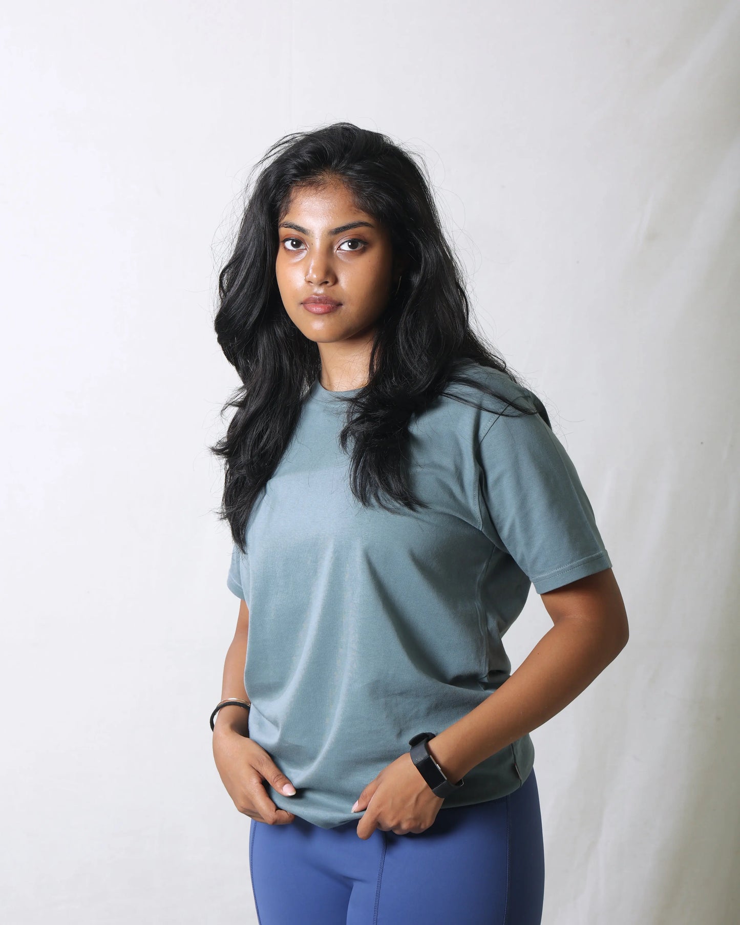 Woman wearing a blue t-shirt and leggings against a white background