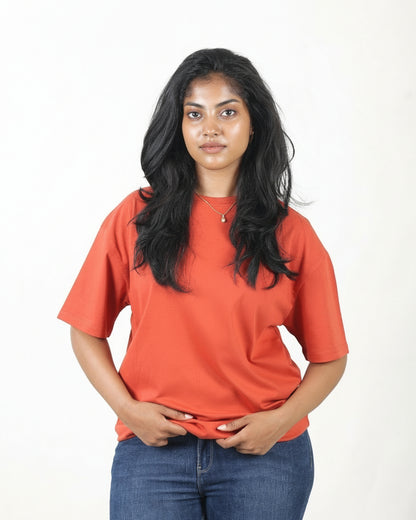 Woman wearing an orange t-shirt and blue jeans on a white background