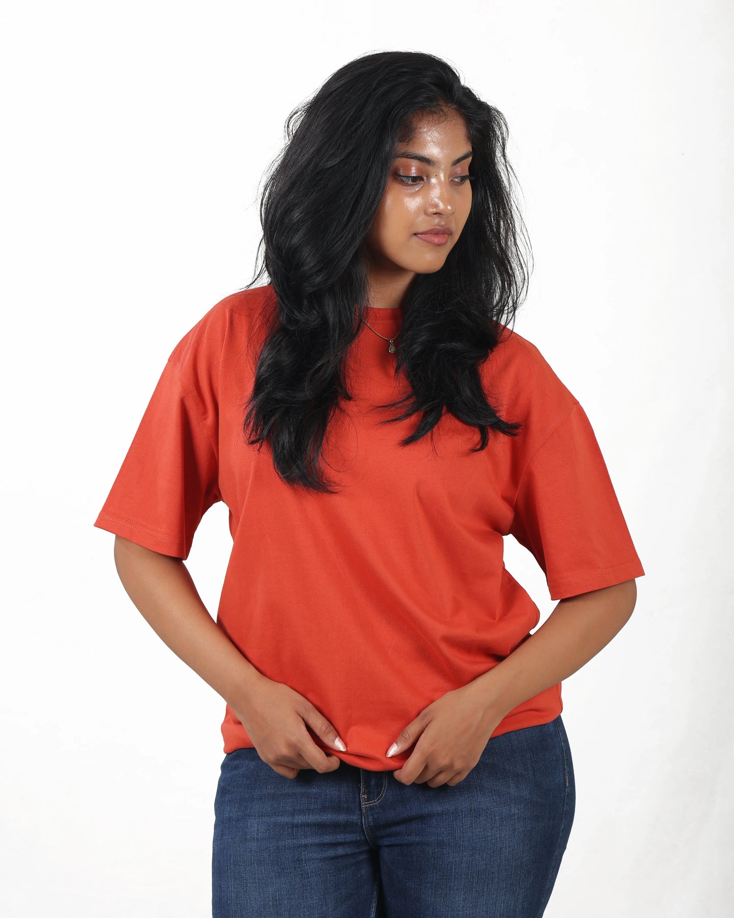 Woman wearing an orange t-shirt and blue jeans on a white background