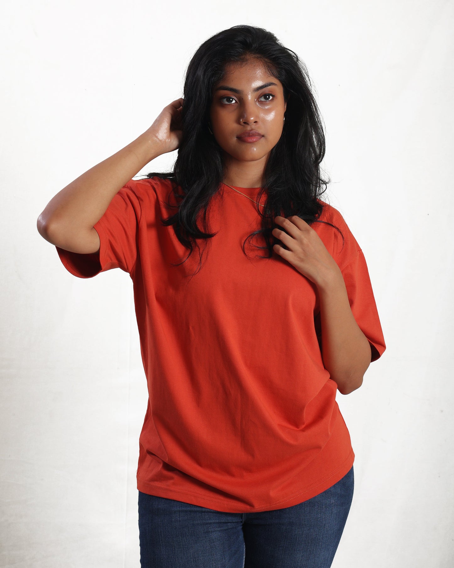 Woman wearing a red t-shirt and blue jeans on a white background