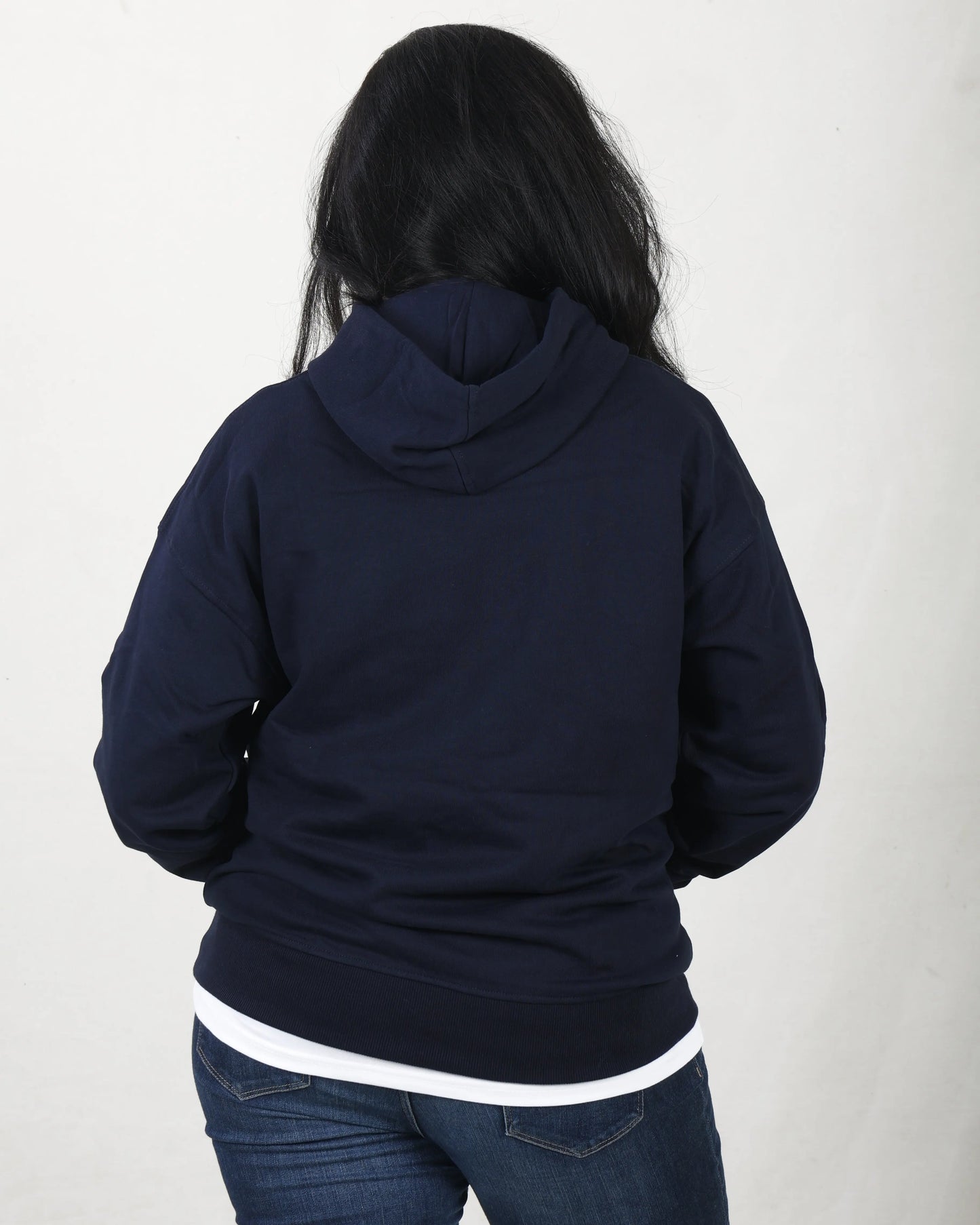 Person wearing a navy blue hoodie with a white stripe on a plain background