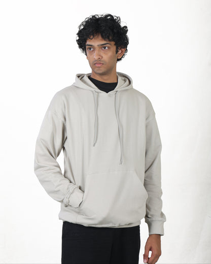 Person wearing a light gray hoodie on a white background