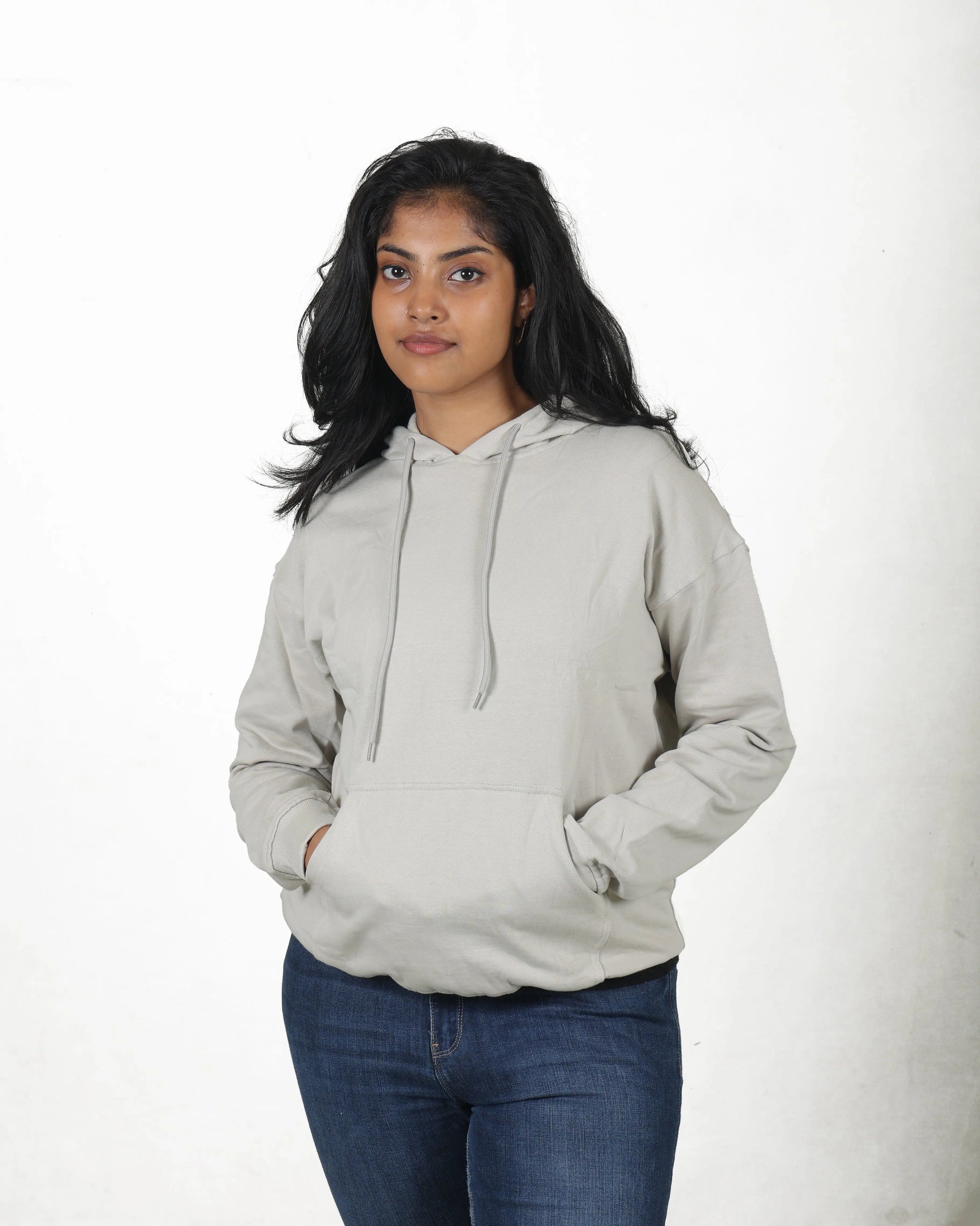 Person wearing a light gray hoodie and blue jeans on a white background