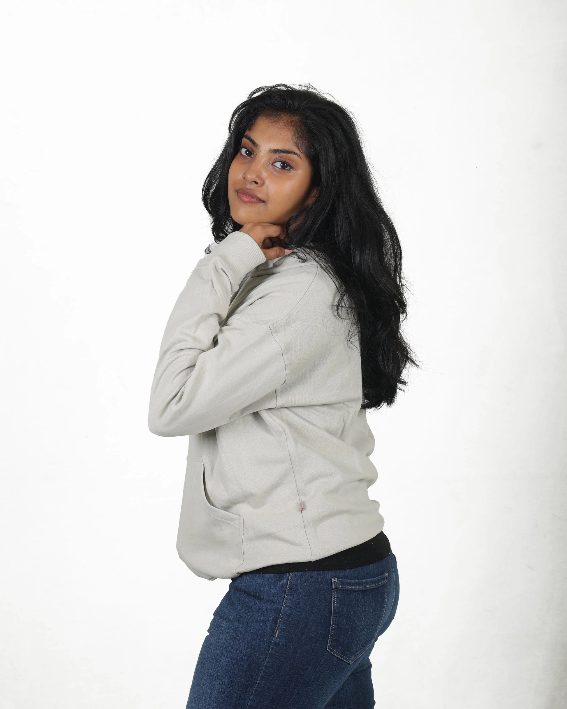 Woman wearing a light gray jacket and blue jeans on a white background