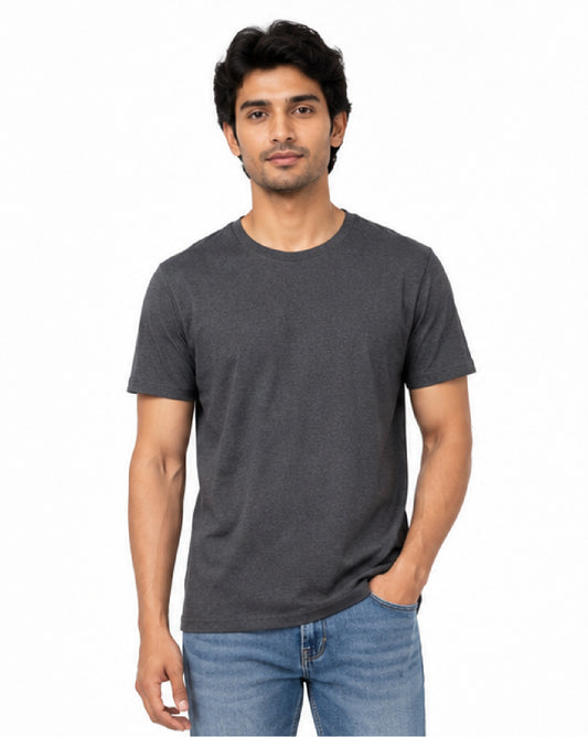 A man wearing a dark gray crew-neck t-shirt and blue jeans, standing against a plain white background.