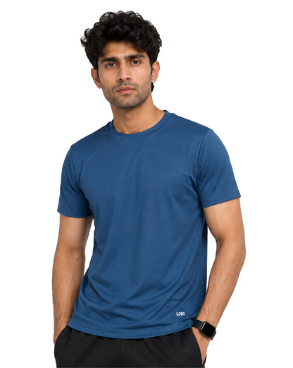 A man wearing a short-sleeve crew-neck athletic t-shirt in a medium blue color, paired with black shorts, against a plain white background.