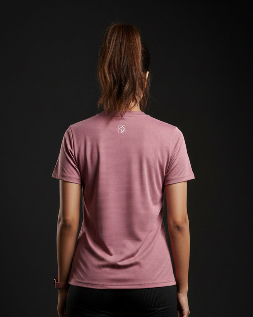 Person wearing a pink t-shirt with a logo on the back against a black background