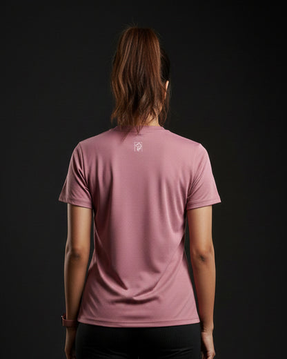 Person wearing a pink t-shirt with a logo on the back against a black background