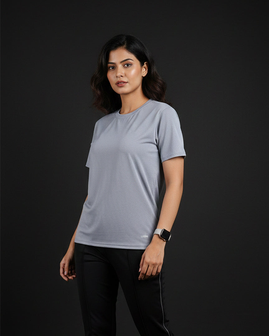 Woman wearing a light gray t-shirt and black pants on a dark background