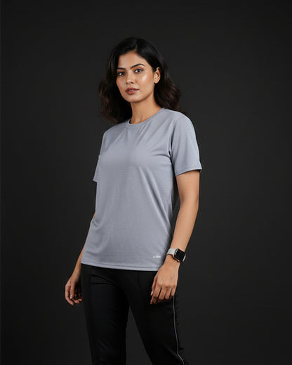 Woman wearing a light gray t-shirt and black pants on a dark background