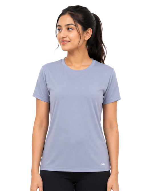 A woman wearing a light periwinkle blue short-sleeve crewneck athletic t-shirt, paired with black leggings, photographed against a solid white background.
