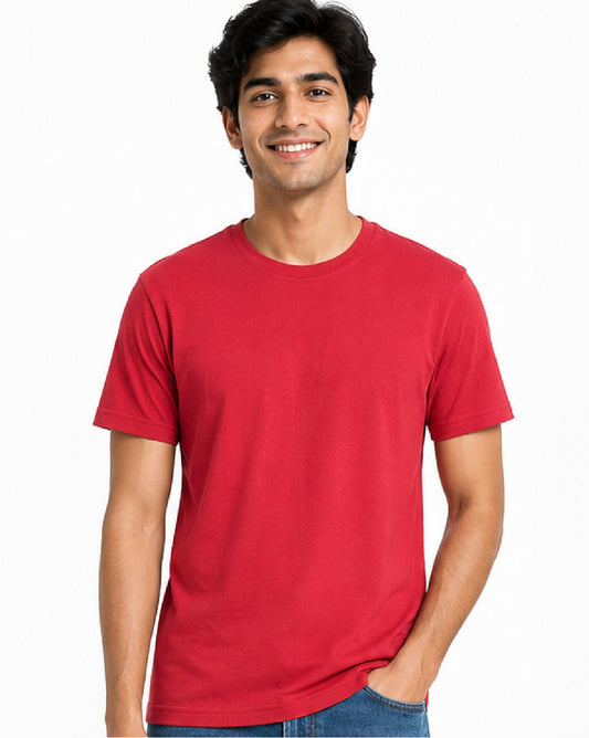 A smiling man wearing a solid red crewneck t-shirt and blue jeans, standing against a plain white background.